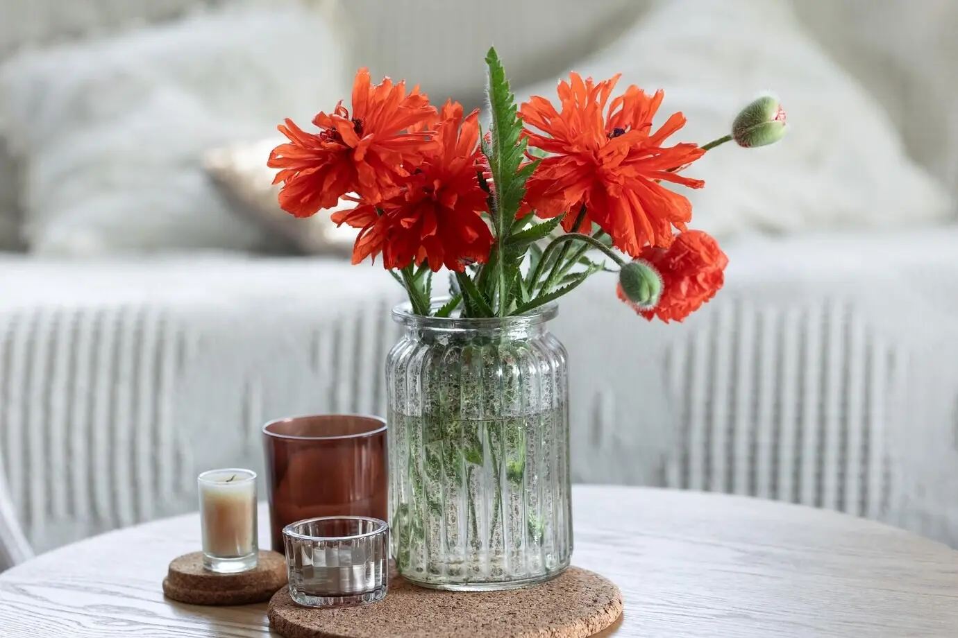 Eine minimalistische Komposition mit roten Mohnblumen in einer Vase und Kerzen zu Hause.